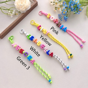 Peut inclure: Quatre porte-cl&eacute;s &agrave; perles color&eacute;es &eacute;pelant des noms : AURORA, ISABELLA, EMILY et SOPHIA. Chaque porte-cl&eacute;s est dot&eacute; d'un cordon de couleur diff&eacute;rente : vert, blanc, jaune et rose. Les noms sont &eacute;pel&eacute;s avec des perles de lettres color&eacute;es.