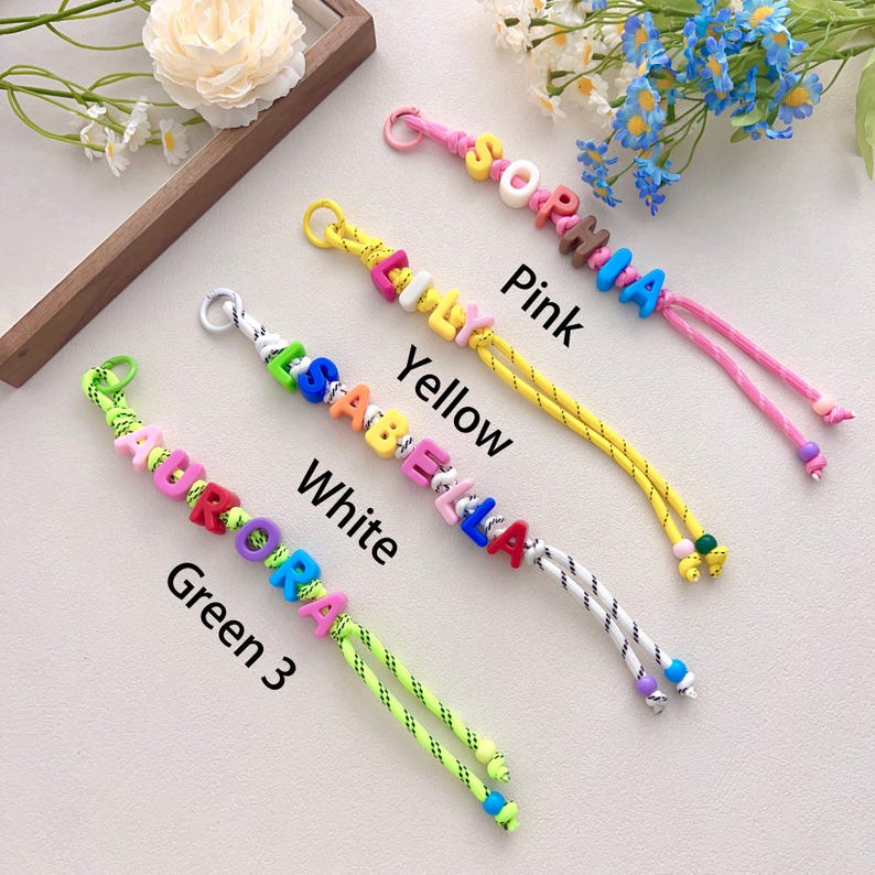 Peut inclure: Quatre porte-cl&eacute;s &agrave; perles color&eacute;es &eacute;pelant des noms : AURORA, ISABELLA, EMILY et SOPHIA. Chaque porte-cl&eacute;s est dot&eacute; d'un cordon de couleur diff&eacute;rente : vert, blanc, jaune et rose. Les noms sont &eacute;pel&eacute;s avec des perles de lettres color&eacute;es.