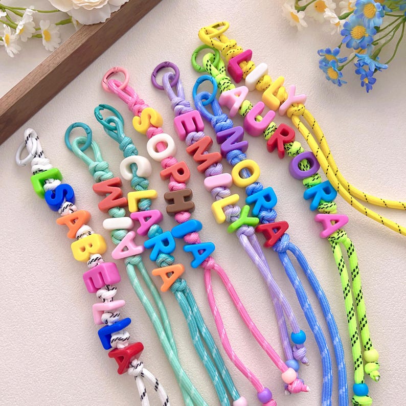Peut inclure: Plusieurs porte-cl&eacute;s &agrave; perles color&eacute;es &eacute;pelant des noms. Chaque porte-cl&eacute; pr&eacute;sente un nom diff&eacute;rent avec des lettres vives et individuelles. Les cordons sont de diff&eacute;rentes couleurs, dont le rose, le bleu et le jaune. Un accessoire personnalis&eacute; et amusant.