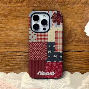 Op de afbeelding: Een telefoonhoesje in patchwork-stijl met verschillende patronen, waaronder harten, ruiten en bloemmotieven in rood, crème en marineblauw. De naam "Hannah" staat in witte letters onderaan. De hoes heeft een camera-uitsparing.