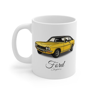 Może przedstawiać: Biały ceramiczny kubek z ilustracją żółtego samochodu Ford Capri i czarnym dachem. Samochód jest przedstawiony w stylu vintage, ze słowami "Ford Capri" kursywą poniżej.