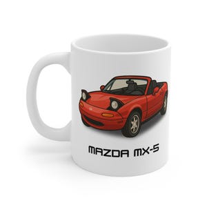 Może przedstawiać: Biały ceramiczny kubek z czerwoną, kreskówkową ilustracją kabrioletu Mazda MX-5. Samochód ma wysuwane reflektory i czarne opony. Tekst "MAZDA MX-5" jest wydrukowany czarnymi, blokowymi literami pod samochodem.