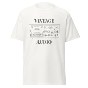 May include: White t-shirt featuring a black line drawing of a vintage audio component. The words "VINTAGE" and "AUDIO" are printed above and below the graphic in a serif font. The design includes details like dials and buttons.