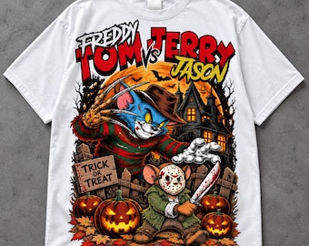 May include: A white t-shirt featuring a graphic print of a cat dressed as Freddy Krueger and a mouse wearing a Jason Voorhees hockey mask. The text reads "FREDDY TOM VS JERRY JASON" and "TRICK OR TREAT" on a wooden sign, set against a spooky house.