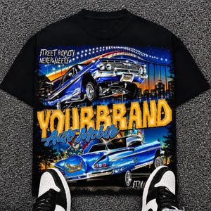 Op de afbeelding: Een zwart t-shirt met korte mouwen en een grafische print van twee blauwe oldtimers, een stadsskyline en een brug bij nacht. De tekst luidt STREET ROYALTY NEVER SLEEPS, YOURBRAND en Auto Mobile. Het ontwerp bevat heldergele en blauwe accenten.
