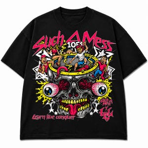 May include: A black t-shirt featuring a graphic print of a large skull with bulging eyes and a tongue sticking out. Above the skull, people are inside a circular structure. The text reads "Such A Mess", "105", and "Learn live conquer".