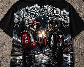 May include: A black short-sleeve t-shirt featuring a graphic of two skeletons in racing gear and caps, holding red cups with fireworks in the background. The text Valley Dreams is printed in a stylized font at the top, with various racing-themed logos.