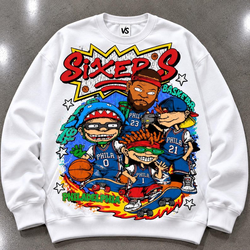 Puede incluir: Una sudadera blanca de cuello redondo con un estampado gr&aacute;fico colorido de cuatro personajes de dibujos animados con camisetas de baloncesto azules de Filadelfia numeradas 0, 23, 21 y 1. El texto SIXERS est&aacute; impreso en rojo arriba.