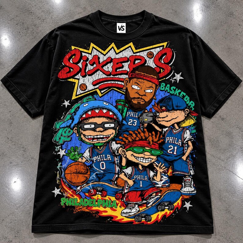 Puede incluir: Una camiseta negra de manga corta con un gran estampado gr&aacute;fico con el texto SIXER'S y PHILADELPHIA. El dise&ntilde;o muestra cuatro personajes de dibujos animados con camisetas de baloncesto azules con los n&uacute;meros 0, 1, 21 y 23, junto a un bal&oacute;n.