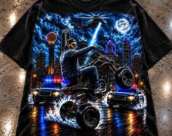 May include: A black short-sleeve t-shirt featuring a graphic print of a person riding an all-terrain vehicle on two wheels through water. The background displays a city skyline at night with police cars, a helicopter, and a full moon.