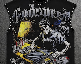 May include: A black sleeveless shirt featuring a graphic of a skeleton wearing a cap and t-shirt while working at a desk with spray paint cans. The word Godspeed is printed in large gothic lettering at the top and on the desk. Silver studs line the collar and arm openings.