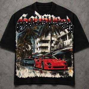 May include: A black short-sleeve t-shirt featuring a graphic print of a red sports car and a blue sports car on a city street with palm trees and buildings. The text "Godspeed" is printed in a large, stylized white and red font at the top.