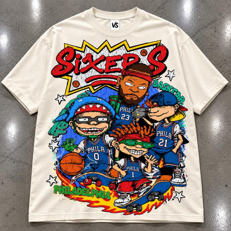 Puede incluir: Una camiseta de manga corta color hueso con un gran estampado gr&aacute;fico que incluye el texto "SIXER'S" y "PHILADELPHIA". El dise&ntilde;o muestra cuatro personajes de dibujos animados con camisetas de baloncesto azules numeradas 0, 1, 21 y 23.
