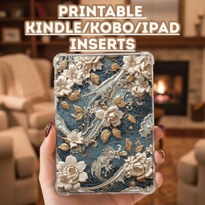 May include: A clear case with a floral design for a Kindle, Kobo, or iPad. The case features white and gold flowers with intricate details on a blue background. The text "PRINTABLE KINDLE/KOBO/IPAD INSERTS" is at the top.