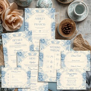 May include: A selection of wedding stationery featuring a cream and blue floral design. The set includes invitations, RSVP cards, a menu, and a wedding timeline. The text includes the names "Ashley & Francis" and event details.