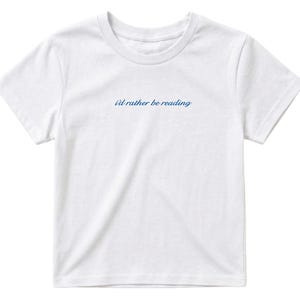 May include: White t-shirt with a crew neck and short sleeves. The text "i'd rather be reading" is printed in a cursive blue font across the chest. The shirt is made of a soft, lightweight material.