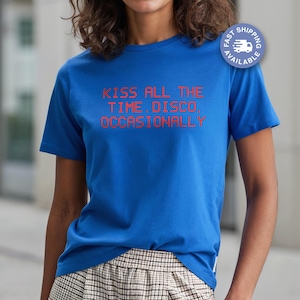 Könnte beinhalten: Ein königsblaues T-Shirt mit dem roten Text "KISS ALL THE TIME. DISCO. OCCASIONALLY". Das Shirt hat kurze Ärmel und einen Rundhalsausschnitt. Ein "Schneller Versand"-Abzeichen ist oben rechts sichtbar.