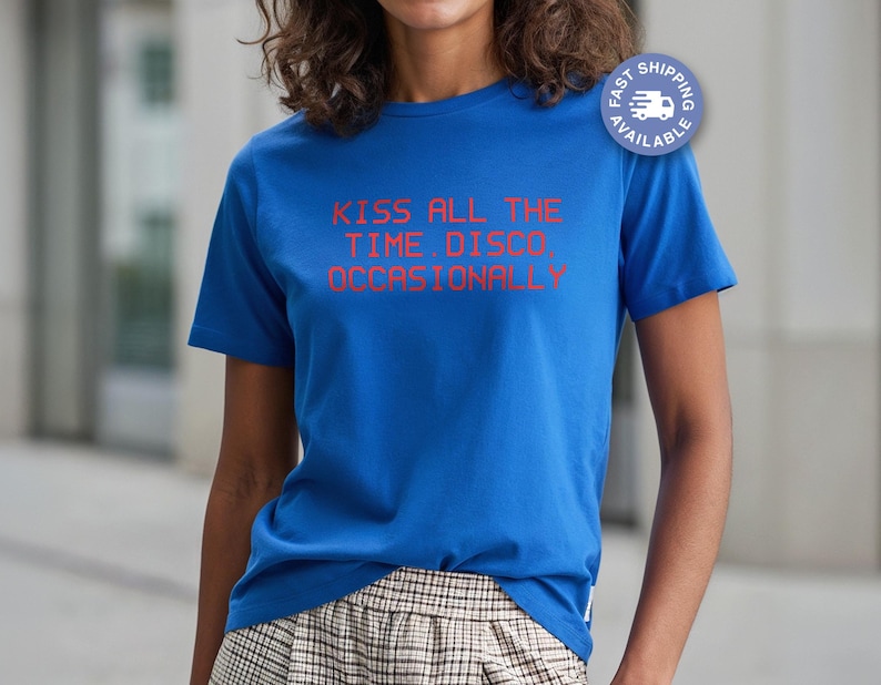 May include: A royal blue t-shirt with the text "KISS ALL THE TIME. DISCO. OCCASIONALLY" in red. The shirt has short sleeves and a crew neck. A fast shipping badge is visible on the upper right.