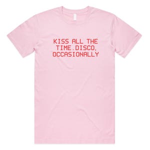 May include: A light pink t-shirt with a crew neck. The shirt features red text that reads "KISS ALL THE TIME. DISCO, OCCASIONALLY". The shirt is made of a soft material and has short sleeves.
