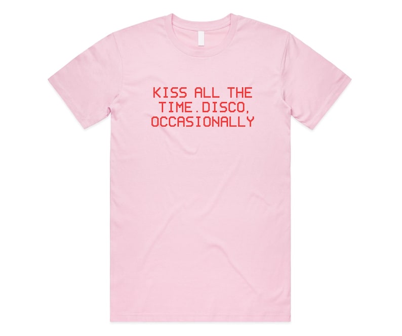 May include: A light pink t-shirt with a crew neck. The shirt features red text that reads "KISS ALL THE TIME. DISCO, OCCASIONALLY". The shirt is made of a soft material and has short sleeves.