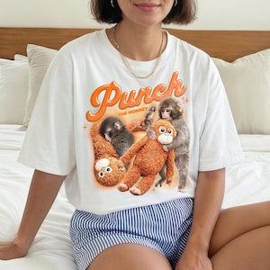 May include: A white ceramic mug with a black handle and the text "But First, Coffee" in a bold, black font. The mug is set against a neutral background, highlighting its simple design.