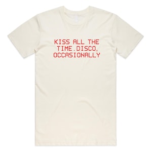 May include: Cream-colored t-shirt with the red text "KISS ALL THE TIME. DISCO, OCCASIONALLY" printed across the front. The shirt has short sleeves and a crew neck.