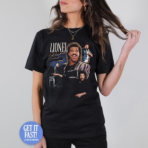 May include: Black t-shirt featuring a graphic of Lionel Richie with the text "Lionel Richie" in a vintage style. The design includes multiple images of the singer. The shirt is worn by a person.