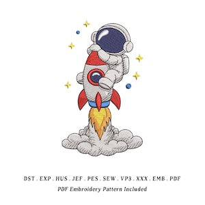 Könnte beinhalten: Gesticktes Design mit einem Astronauten, der eine Rakete hält. Die Rakete ist grau mit roten Akzenten und Flammen. Der Astronaut trägt einen weißen Raumanzug und einen blauen Helm. Gelbe Sterne und blaue Punkte sind verstreut.