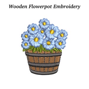 May include: Embroidered design of a flowerpot filled with blue flowers with yellow centers and green leaves. The flowerpot is brown with black bands. The text "Wooden Flowerpot Embroidery" is above the image.