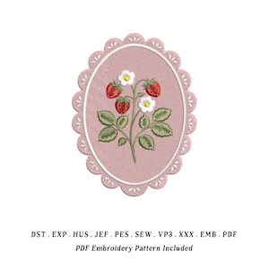 May include: An oval-shaped embroidery design featuring a strawberry plant with red berries, white flowers, and green leaves. The design is set against a pink background and framed by a scalloped edge. The text "PDF Embroidery Pattern Included" is below the design.