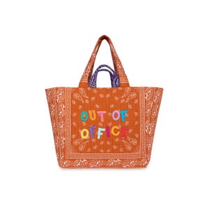 May include: A large orange tote bag with a paisley pattern and the words "OUT OF OFFICE" in colorful, embroidered letters. The bag has two handles and a purple accent on the inside handle.