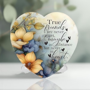 May include: A heart-shaped glass ornament with a floral design and the quote "True friends are never apart, maybe in distance but never in heart."