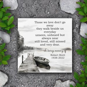 May include: A black and white image of a wooden dock extending over a lake with a small boat tied to it. The image is accompanied by a poem about those who have passed away, and a memorial inscription for Robert Brett, 1938-2022.