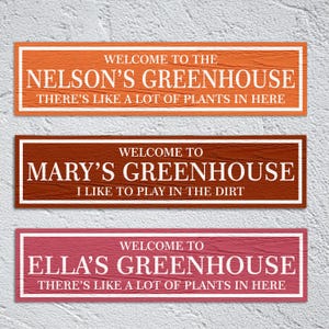 May include: Three wooden signs with white text on a textured background. The signs read "Welcome to the Nelson's Greenhouse There's like a lot of plants in here", "Welcome to Mary's Greenhouse I like to play in the dirt", and "Welcome to Ella's Greenhouse There's like a lot of plants in here".