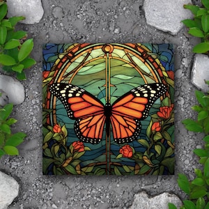 May include: A stained glass style illustration of a monarch butterfly with orange and black wings. The butterfly is centered in a circular frame with a green, blue, and brown background. The frame is surrounded by stylized flowers and leaves.