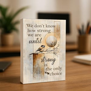 May include: A rectangular canvas art print with a rustic wood-look background. The artwork features a bird perched on a branch, a stylized moon, and the inspirational quote: "We don't know how strong we are until strong is the only choice."