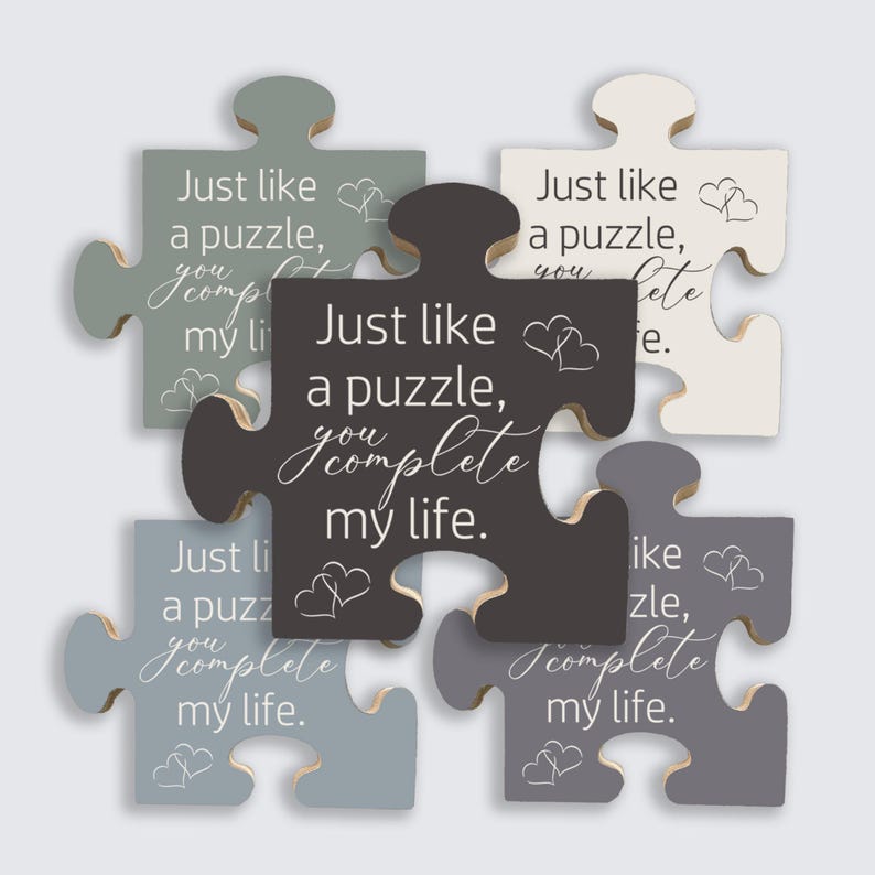 May include: A collection of wooden puzzle pieces in various shades of gray, white, and black. Each piece has the phrase "Just like a puzzle, you complete my life" in white script, along with heart illustrations.