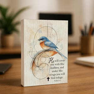 May include: A wooden block featuring a watercolor painting of a bluebird perched on a decorative swirl. The artwork includes the text "He will cover you with His feathers, and under His wings you will find refuge. Psalms 91:4" and a cross.