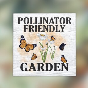 May include: White wooden sign with black text that reads "Pollinator Friendly Garden". The sign features a watercolor illustration of white daisies and orange and black butterflies.