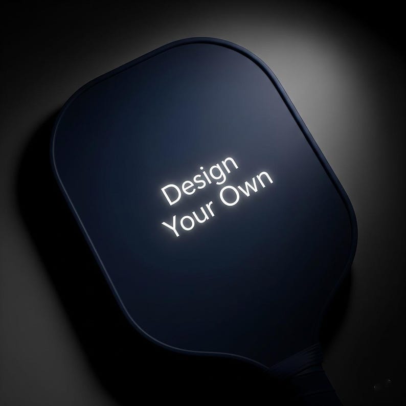 K&ouml;nnte beinhalten: Ein dunkelblaues, abgerundetes rechteckiges Objekt mit den Worten "Design Your Own" in hellem, wei&szlig;em, beleuchtetem Text. Das Objekt hat einen Griff und ist vor einem dunklen Hintergrund platziert.