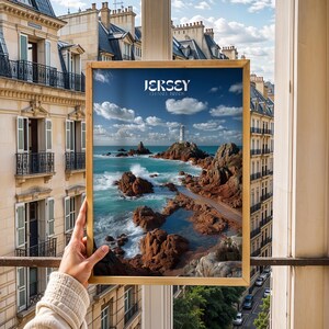 May include: A framed print depicting a coastal scene with a lighthouse. The image shows turquoise water, brown rocks, and a blue sky with clouds. The print has the word "JERSEY" at the top, referencing the Channel Islands.
