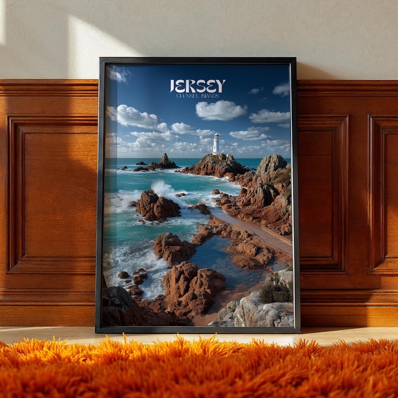 May include: A framed print depicting a coastal scene with a lighthouse on a rocky island. The image shows turquoise water, brown rocks, and a pathway leading to the lighthouse under a blue sky with clouds. The text "JERSEY CHANNEL ISLANDS" is at the top.