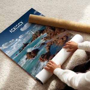 May include: A poster depicting a coastal scene with the words "JERSEY CHANNEL ISLANDS" in white. The image shows a lighthouse, rocks, and turquoise water under a blue sky. A rolled-up poster and a brown tube are also visible.