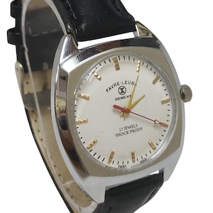 May include: A silver Favre-Leuba Geneve wristwatch with a white face, gold markers, and a black leather strap. The watch face displays "17 Jewels Shock Proof" and "Swiss Made". The watch has a red second hand.