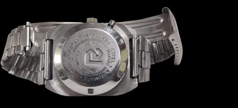 Pu&ograve; includere: Un orologio da polso in acciaio inossidabile con cinturino in metallo argentato. Il quadrante dell'orologio &egrave; visibile, con la scritta "WATER RESISTANT", "STAINLESS STEEL" e "INDIA". L'orologio &egrave; un modello automatico.