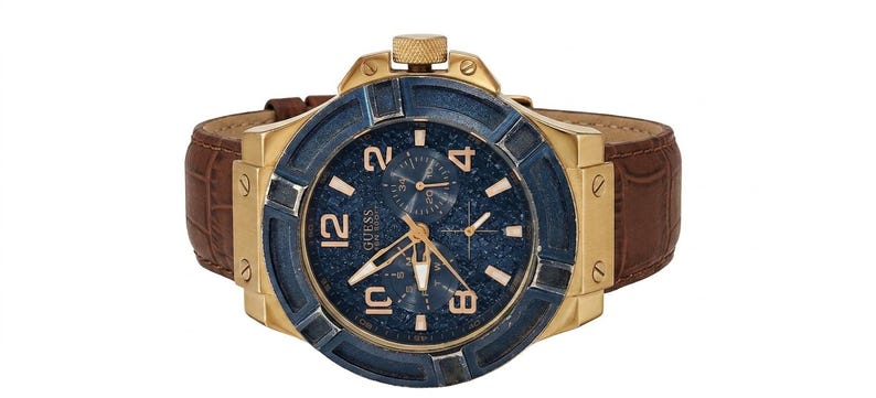 Peut inclure: Une montre Guess dor&eacute;e avec un cadran bleu et un bracelet en cuir marron. Le cadran de la montre pr&eacute;sente des aiguilles et des chiffres dor&eacute;s. La montre a une lunette bleu fonc&eacute; textur&eacute;e et une couronne dor&eacute;e.