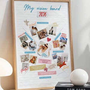 Op de afbeelding: Een ingelijst vision board met de tekst "My vision board 2026" en foto's. Een witte lamp, een witte bol en twee boeken staan op een witte tafel. De boeken heten "TOM FORD" en "GETTING LIVE".