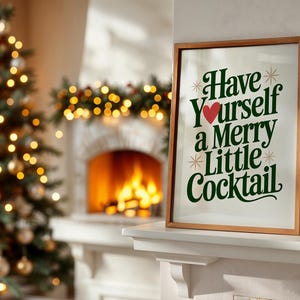 May include: A framed print with the text "Have Yourself a Merry Little Cocktail" in green and red, displayed on a white mantel. A Christmas tree with gold ornaments and lights is in the background, along with a fireplace.
