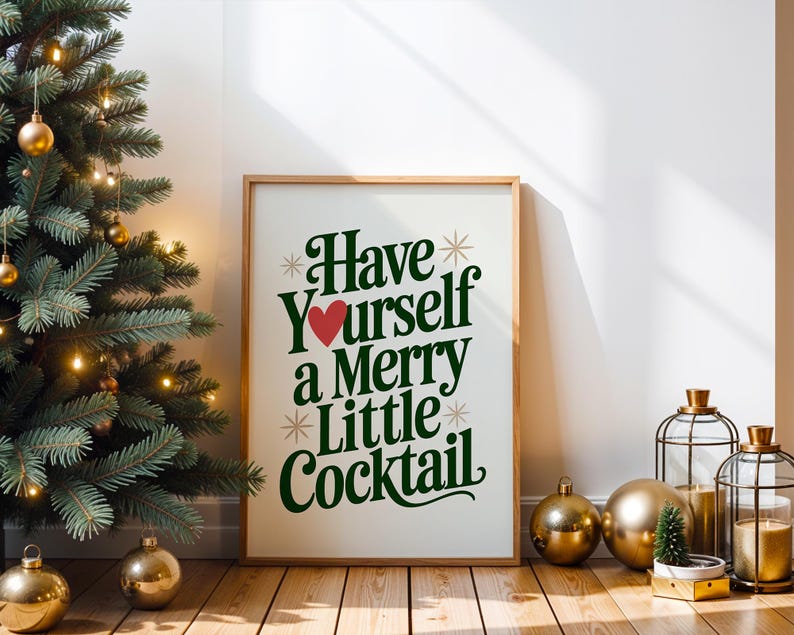 May include: A framed print with the text "Have Yourself a Merry Little Cocktail" in green and a red heart. The print is displayed next to a decorated Christmas tree with gold ornaments and lights. Gold ornaments and candle holders are also present.