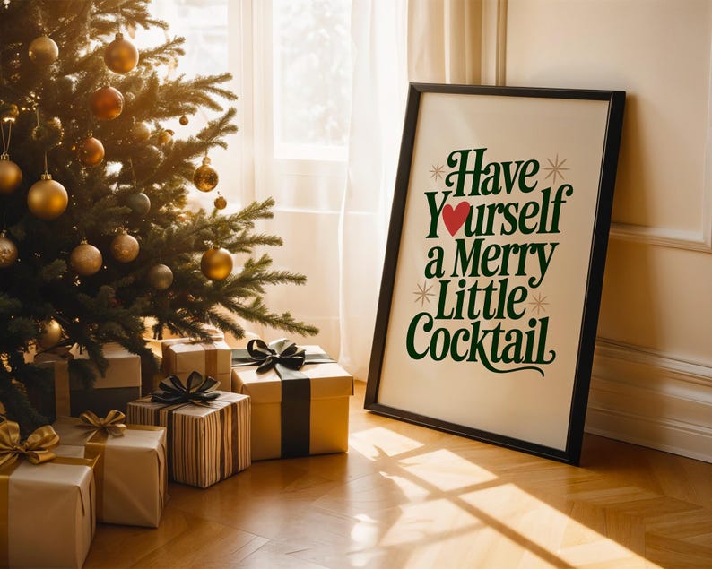 May include: A framed print with the text "Have Yourself a Merry Little Cocktail" in green and red, leaning against a wall. A Christmas tree with gold ornaments and wrapped gifts with bows are in the foreground, creating a festive holiday scene.